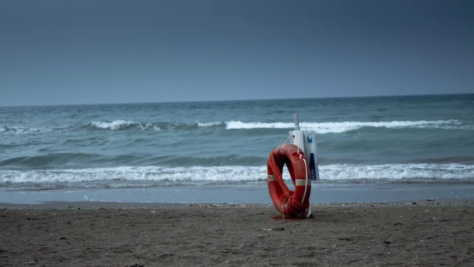 Livboj ensam på stranden mot bakgrund av öppet hav. Foto.